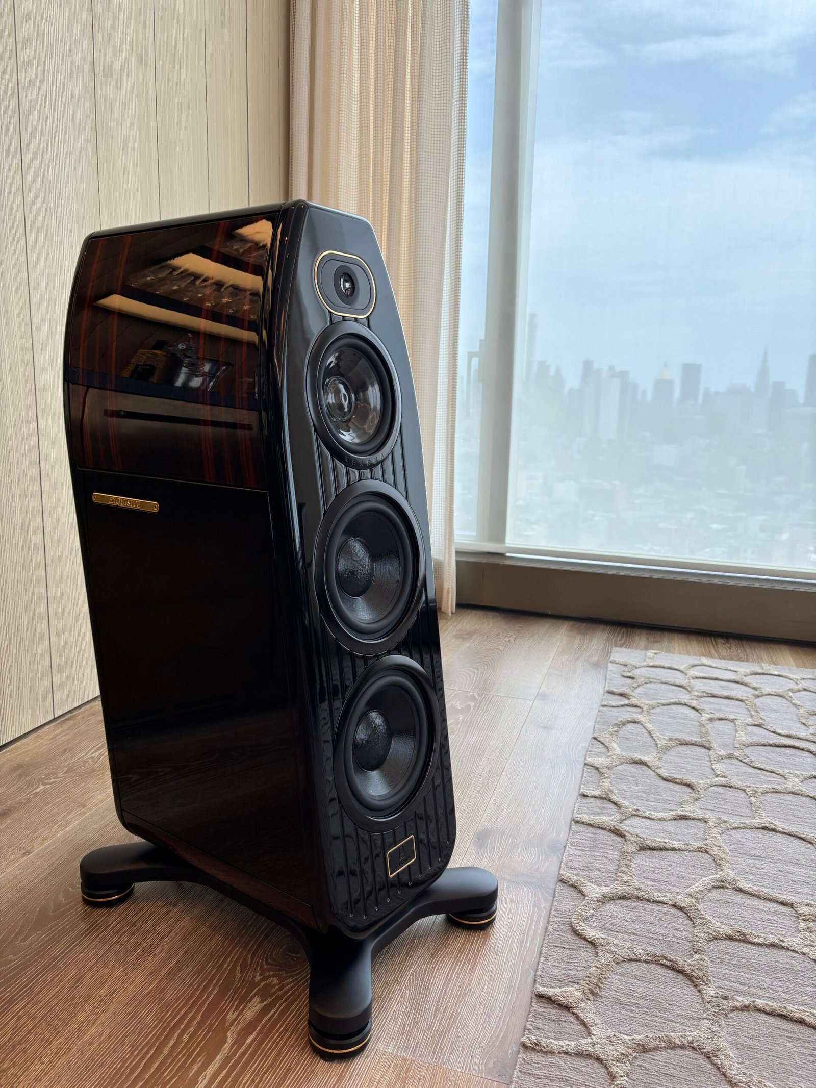 Floor-standing speaker set up by a window with city view, NYC