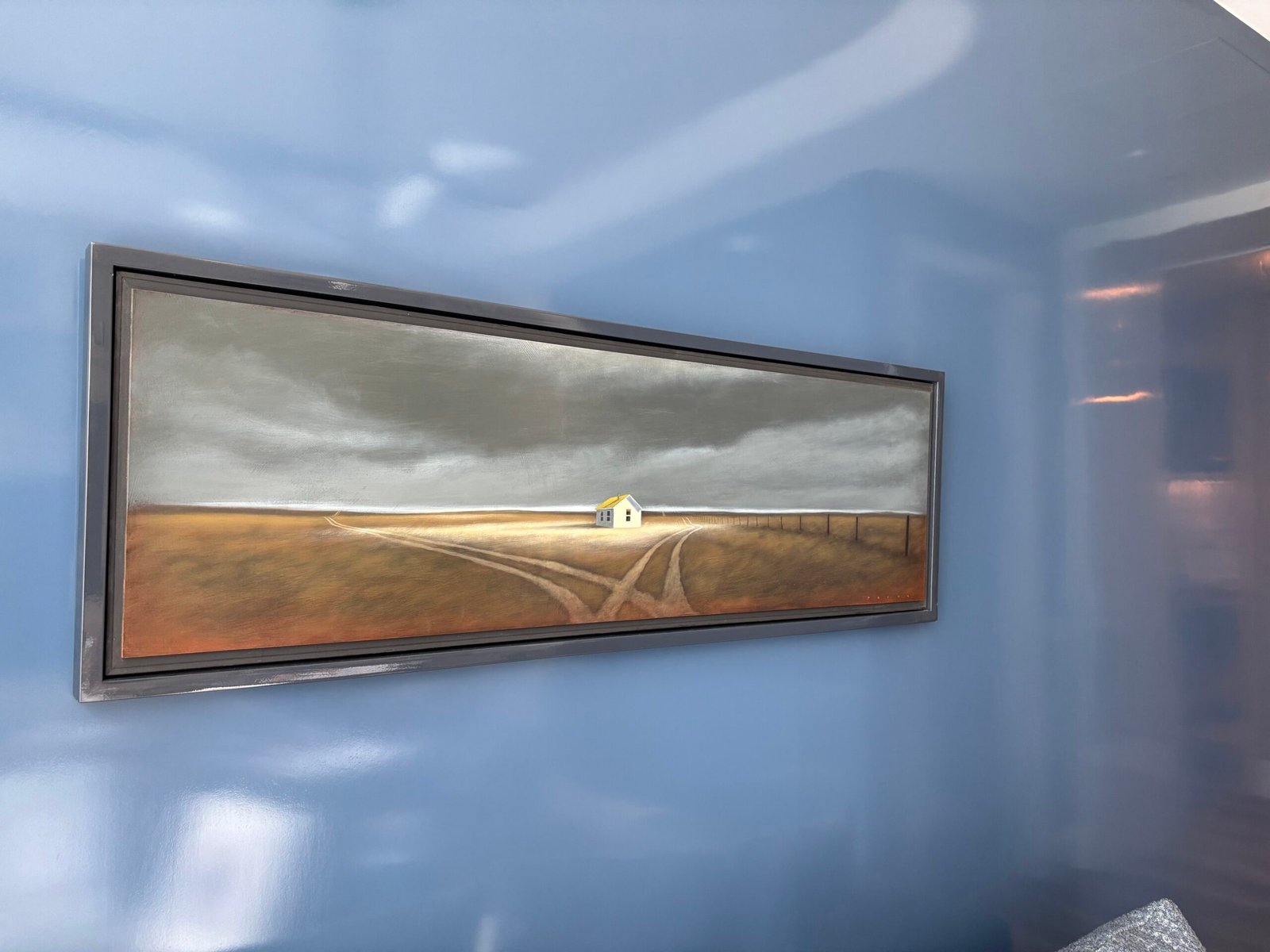 Framed landscape painting hung on a blue wall, NYC