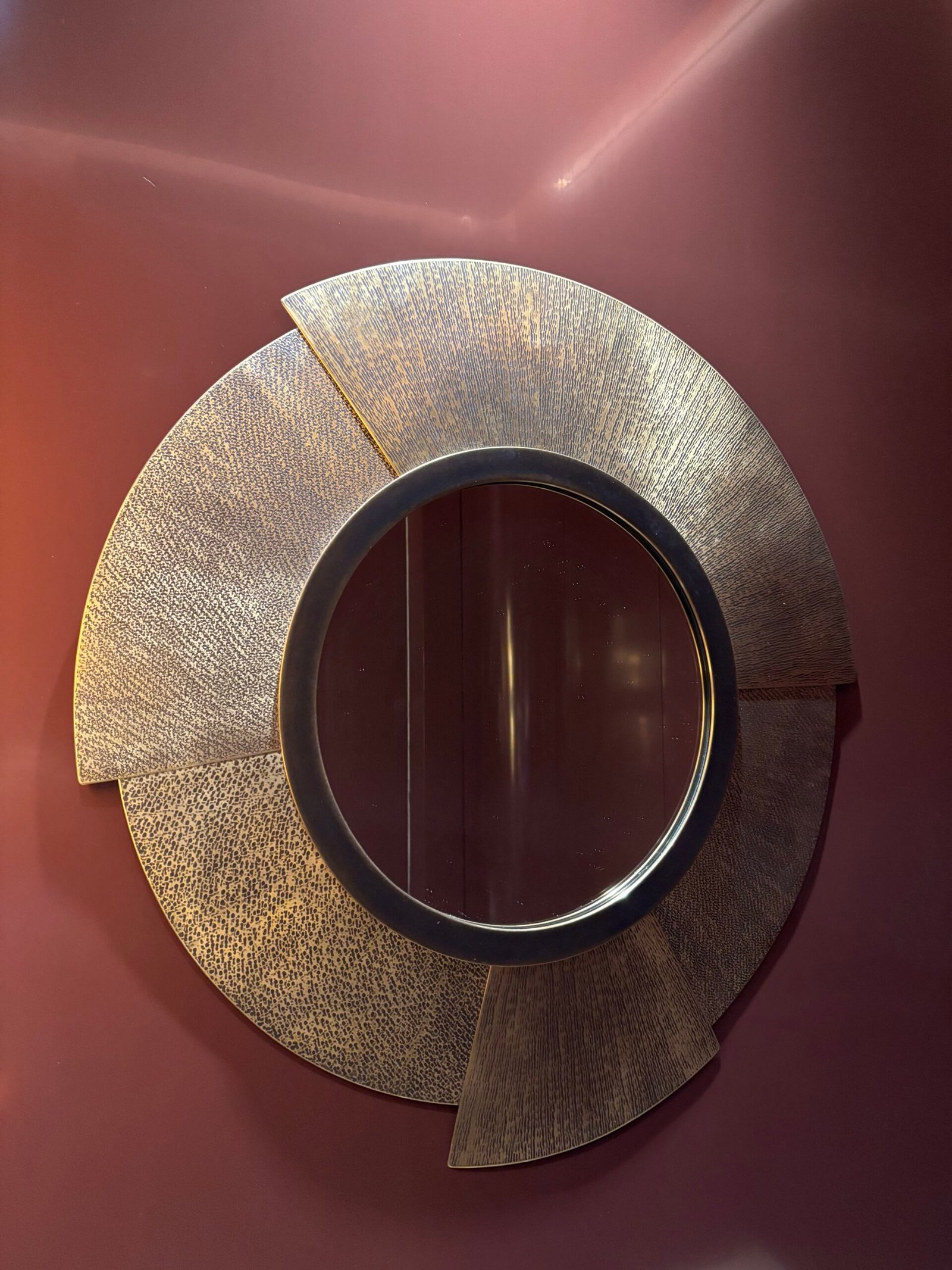Round hammered metal mirror mounted on a red wall, NYC