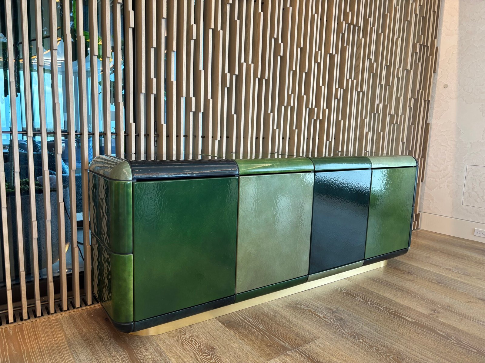 Green lacquer sideboard installed against a wood slat wall, NYC