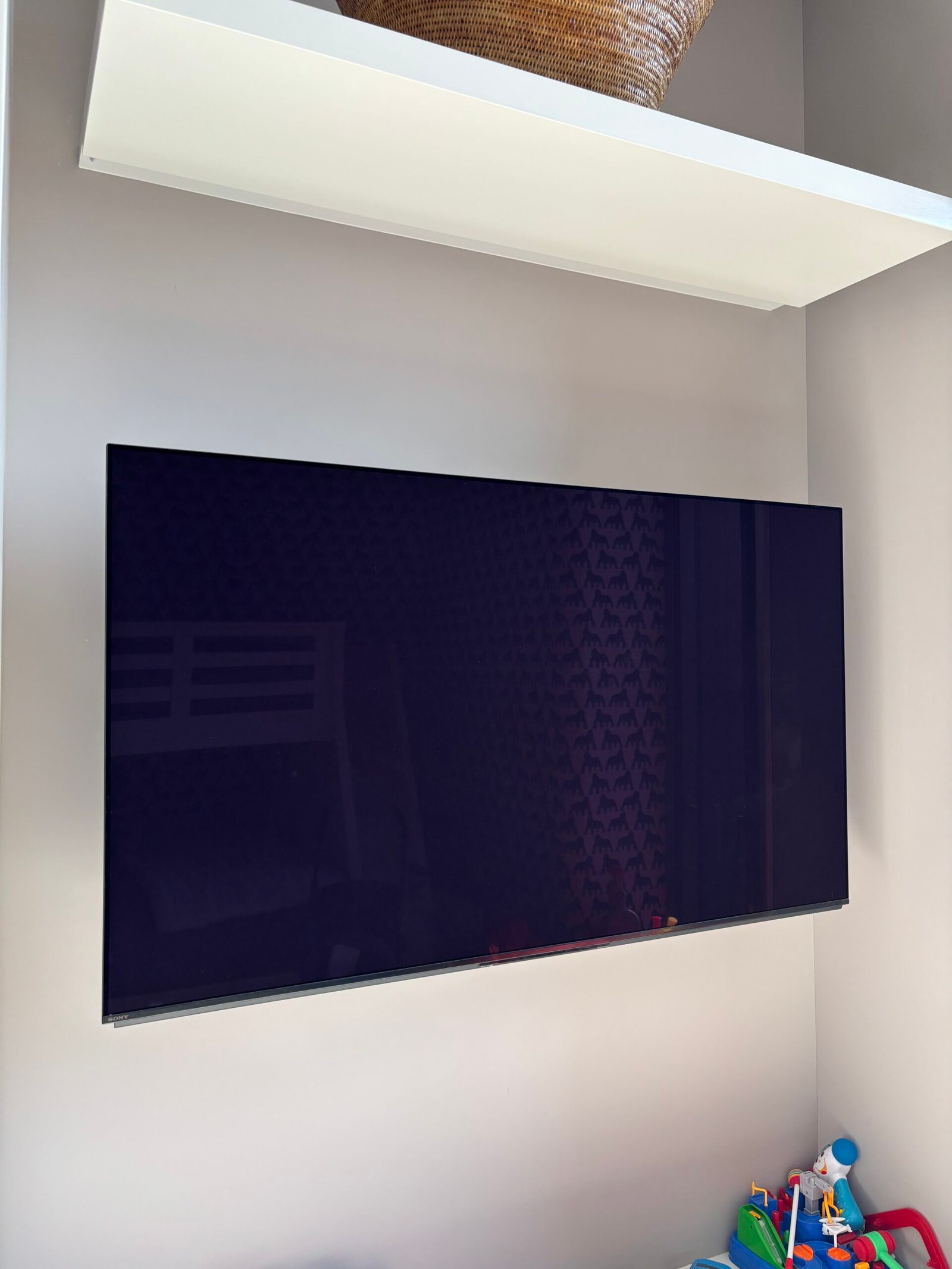 Large flat screen TV mounted on a white wall, NYC apartment