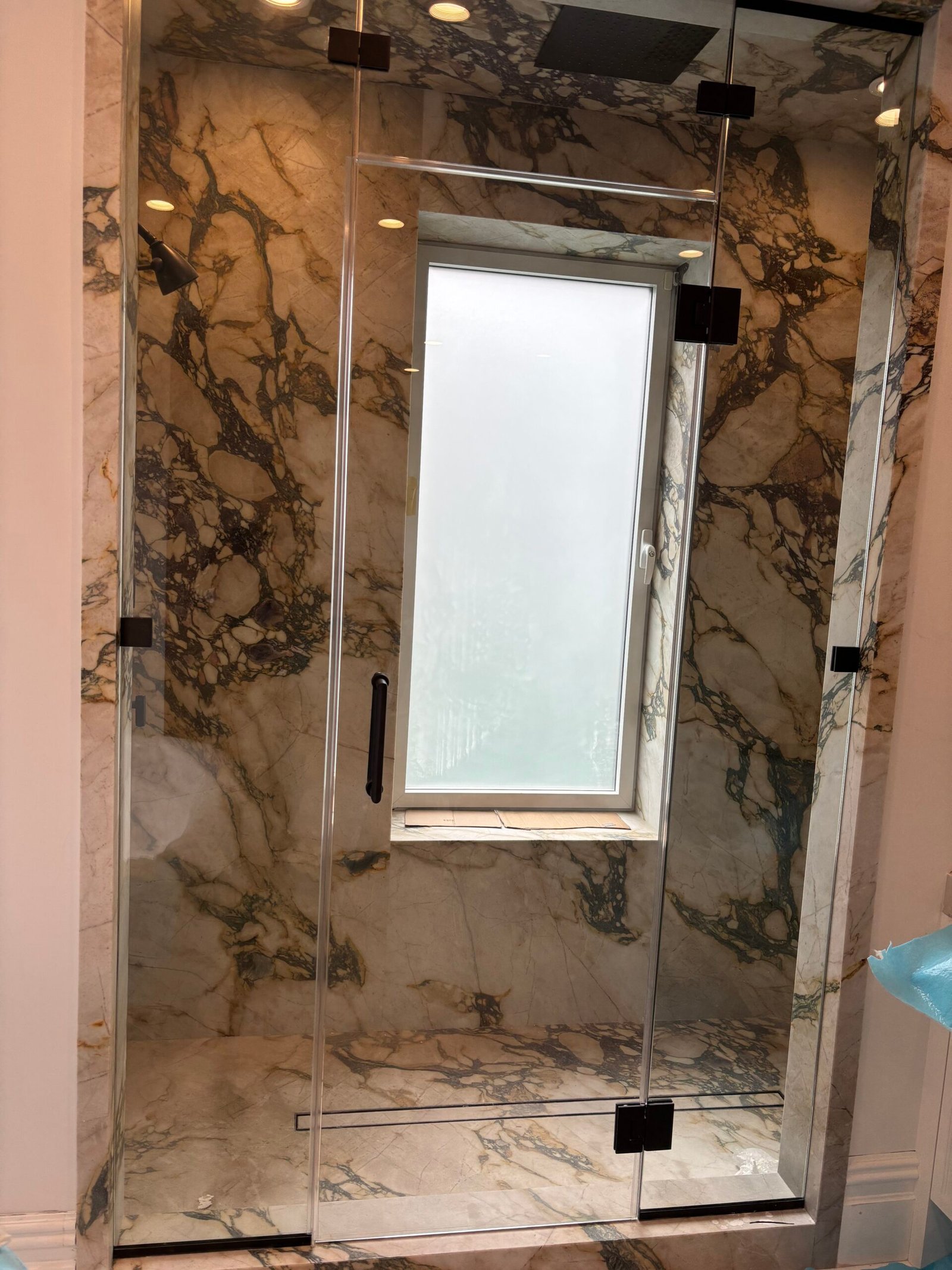 Glass shower door installed with marble walls, NYC bathroom