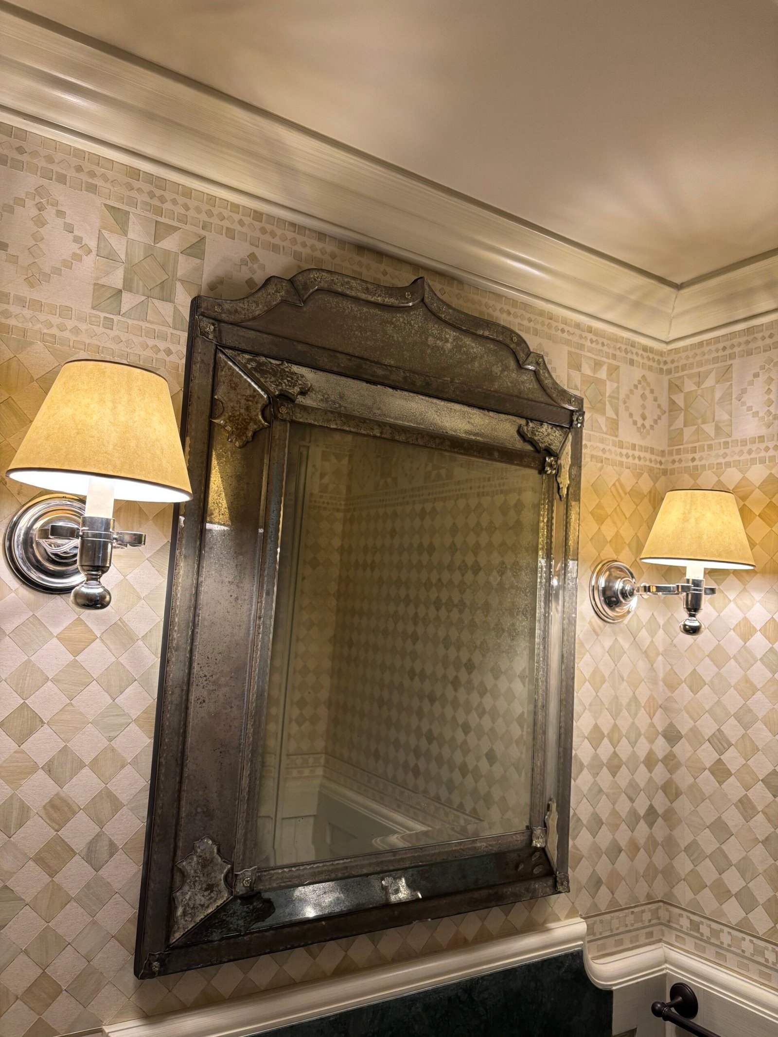 Antique mirror hung between two wall sconces, NYC