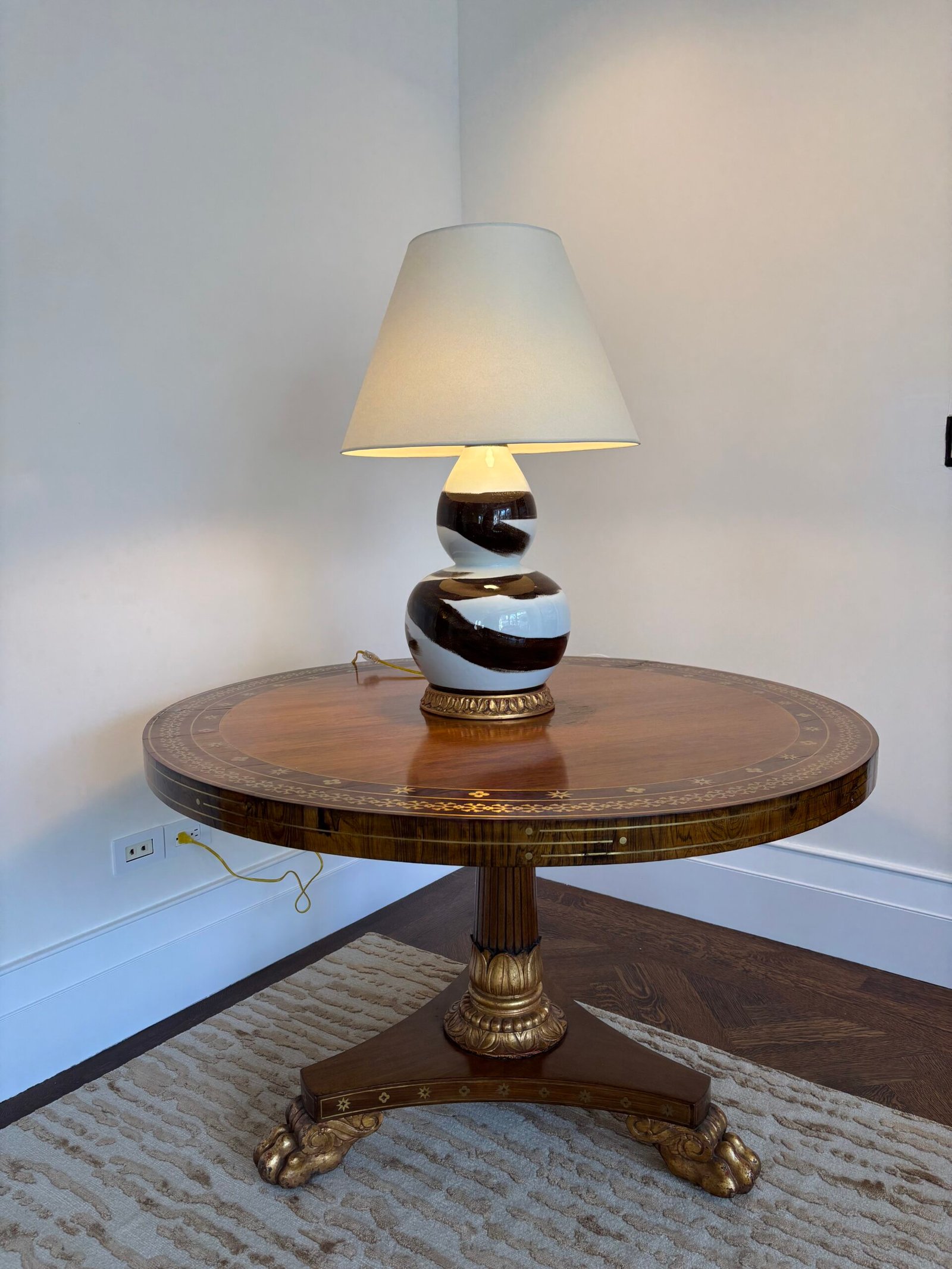 Round wood table with lamp placed in a corner, NYC