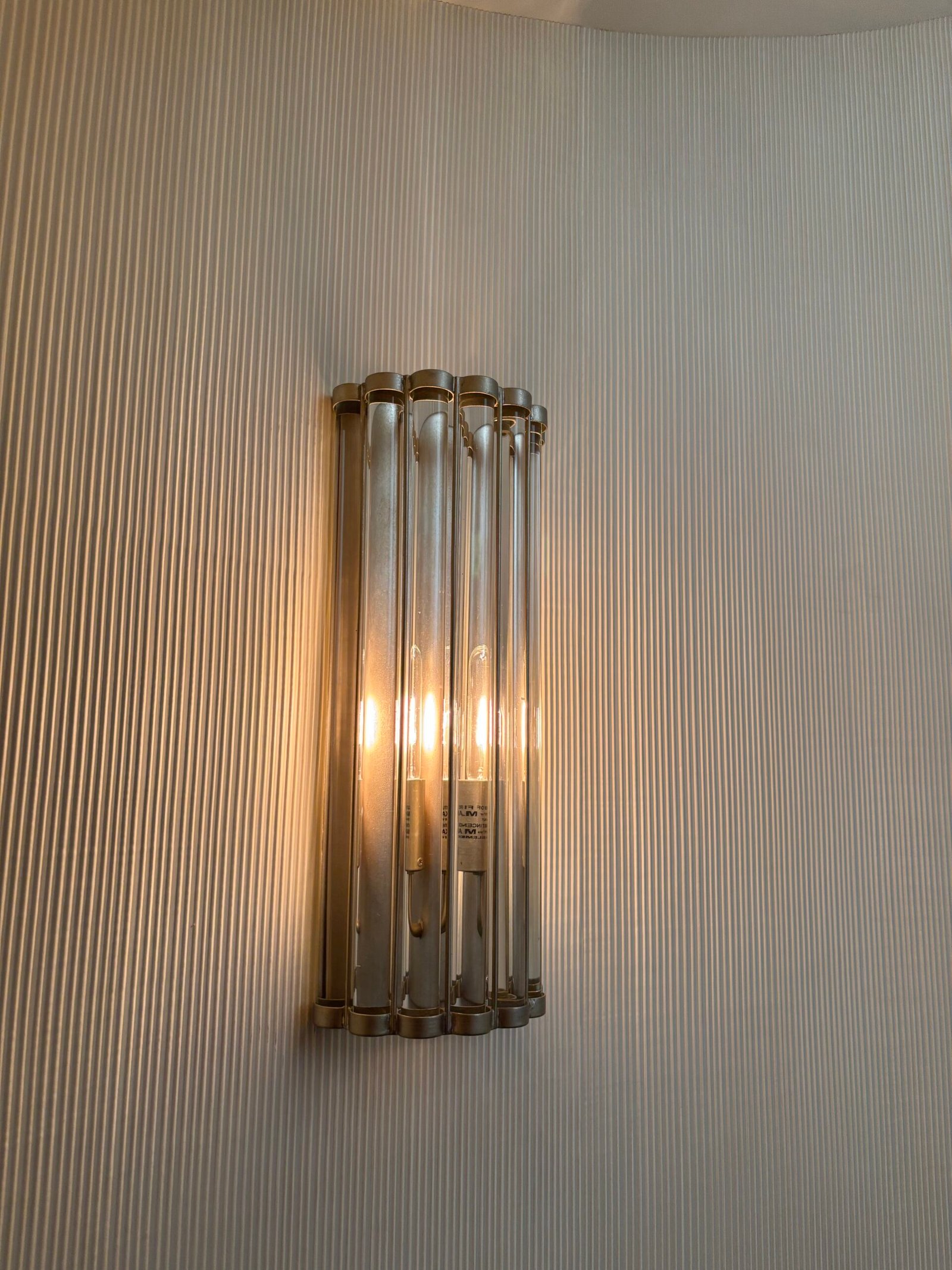Glass tube wall sconce installed on a textured wall, NYC