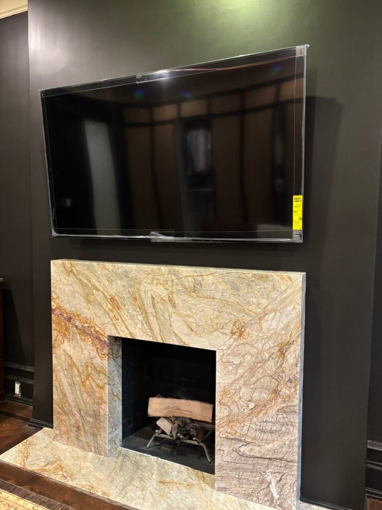 TV mounted above a marble fireplace on a dark wall, NYC