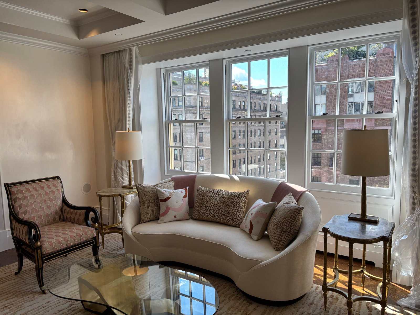 Living room with curved sofa and armchairs by the windows, NYC apartment
